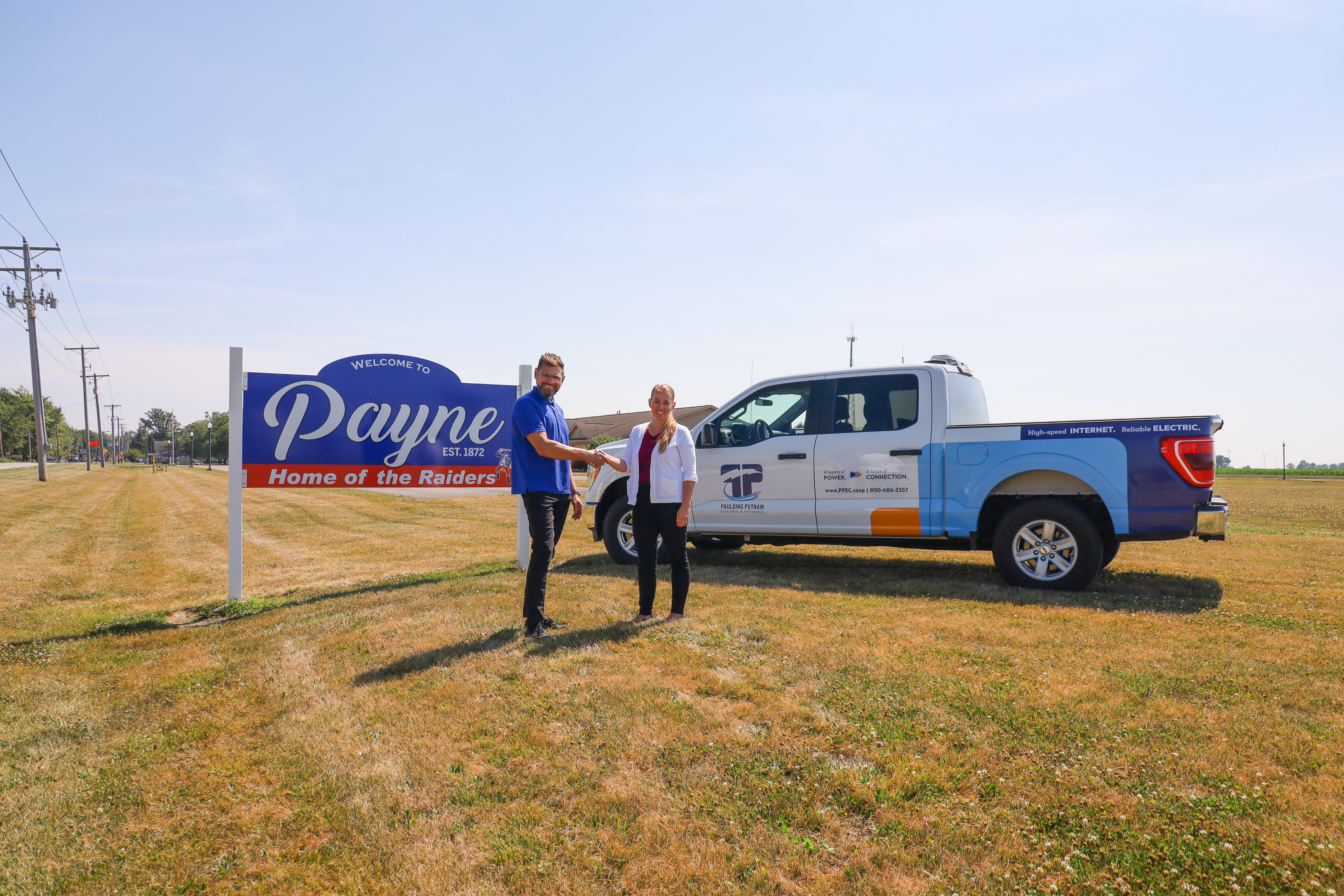 Village of Payne sign and handshake for partnership