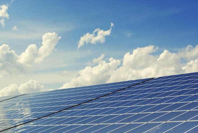 Solar panels lined up under a blue sky.