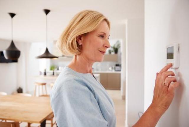 Woman adjusting thermostat